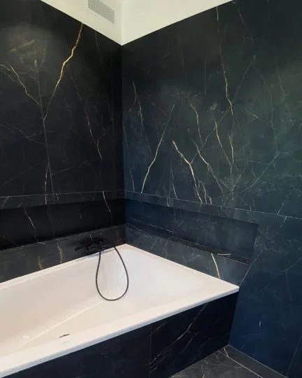 Bagno elegante con rivestimento in gres effetto marmo nero. Venature dorate, posa continua e stile contemporaneo 